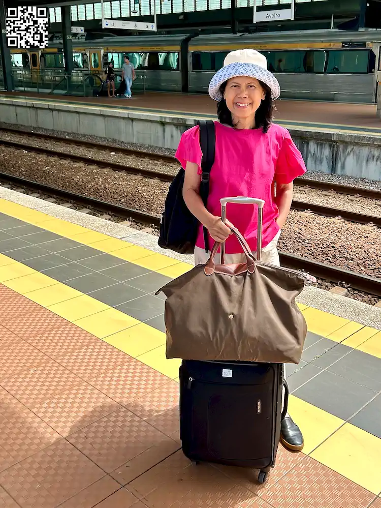 About: Women with luggage standing near the tracks at the station.