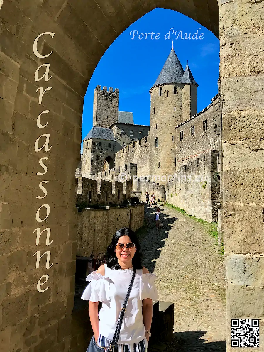 France Carcasonne La Cite Medievale Porte d'Aude, woman standing at the gate with old stone towers in the background.