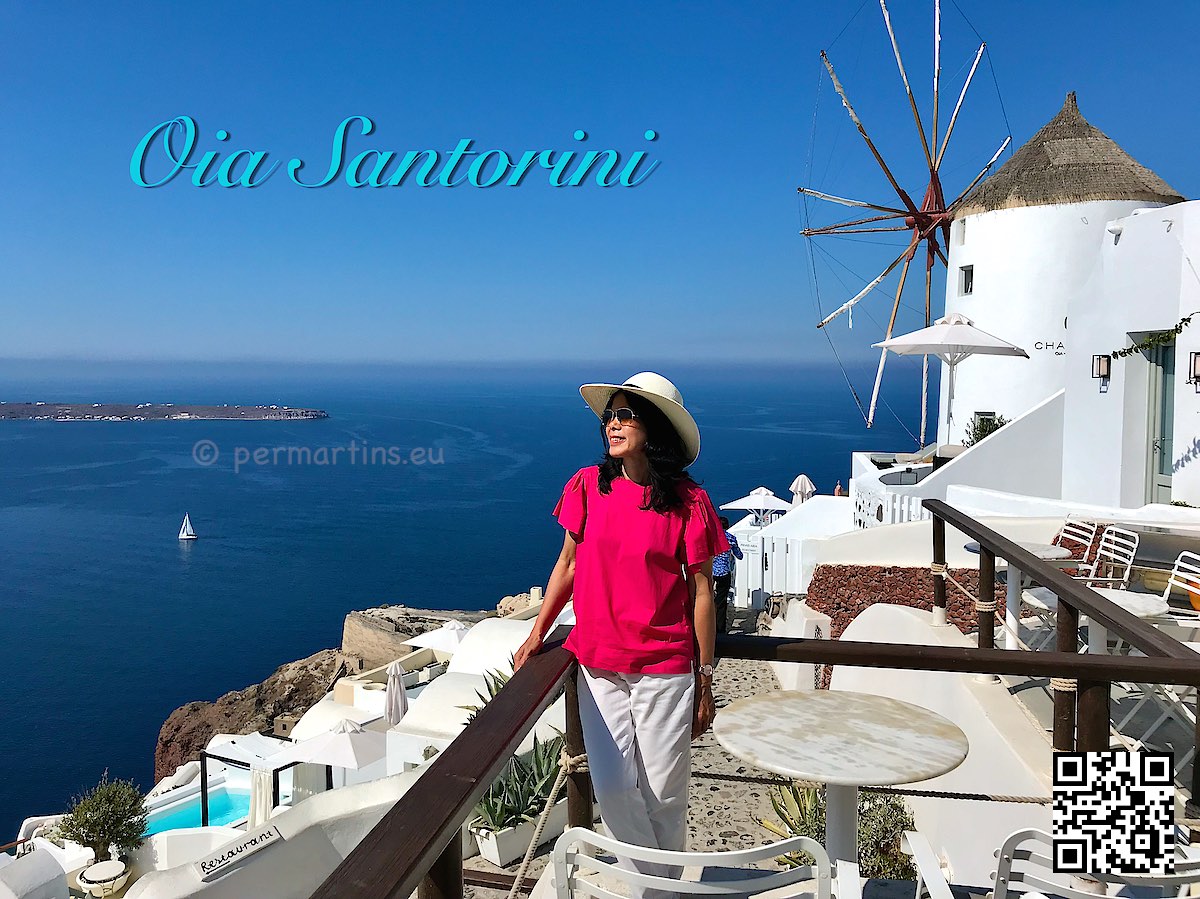 Greece Santorini Oia woman with a hat looking out over the caldera at Sunset Windmill a popular place to watch the sunset.
