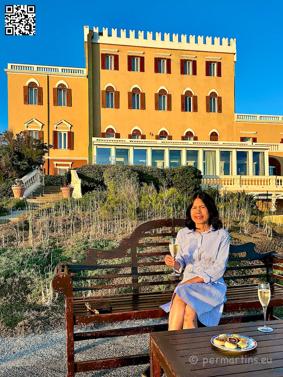 Italy Sardinia Alghero Villa Las Tronas Hotel & Spa, woman enjoying prosecco with appetizers at sunset in front of the hotel.