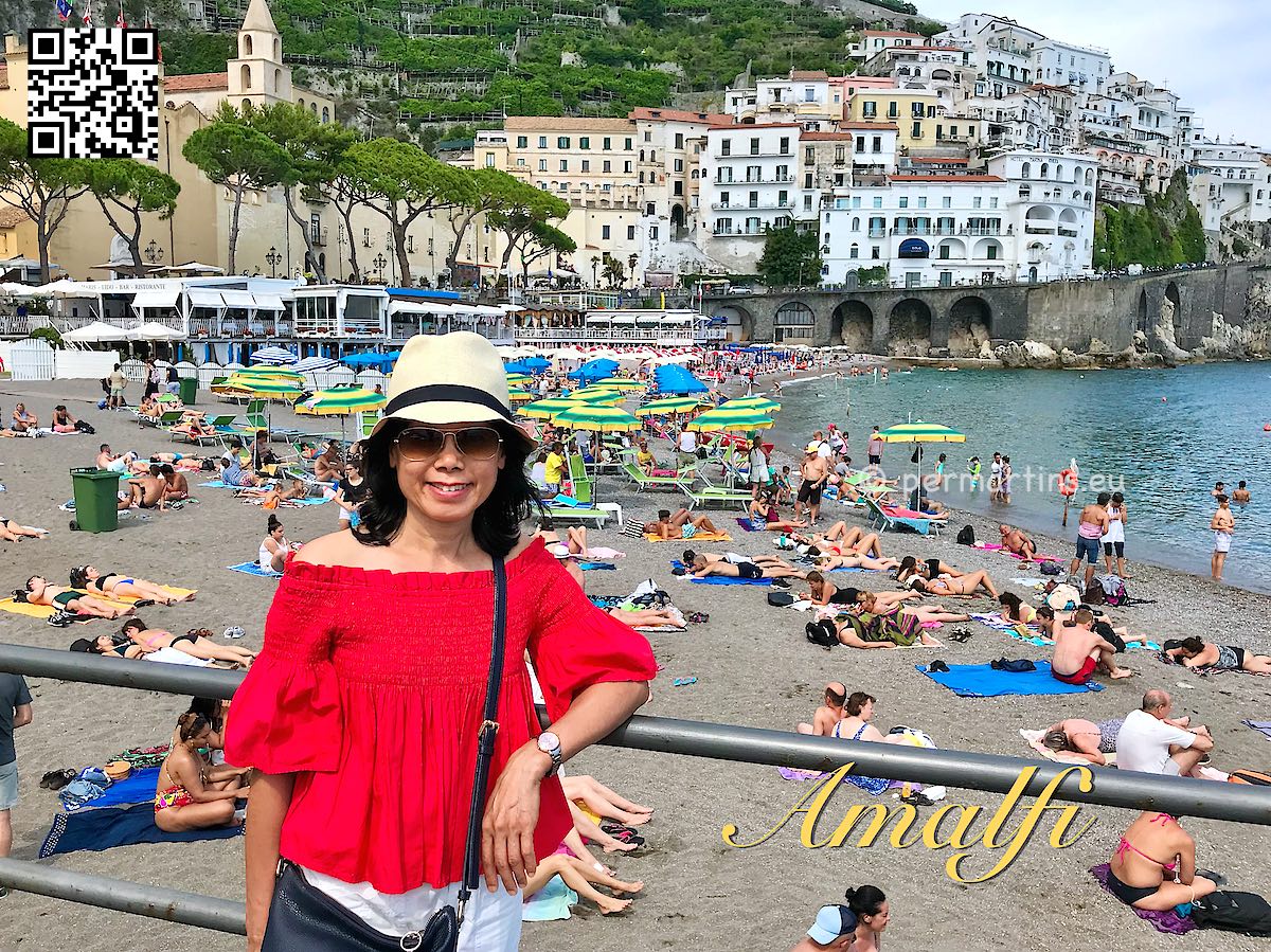 Italy Amalfi woman with hat beach behind her.