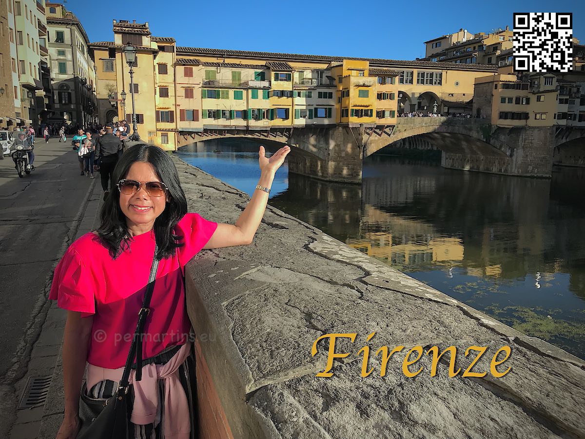Italy Florence Firenze River Arno woman pointing to Ponte Vecchio bridge with shops.