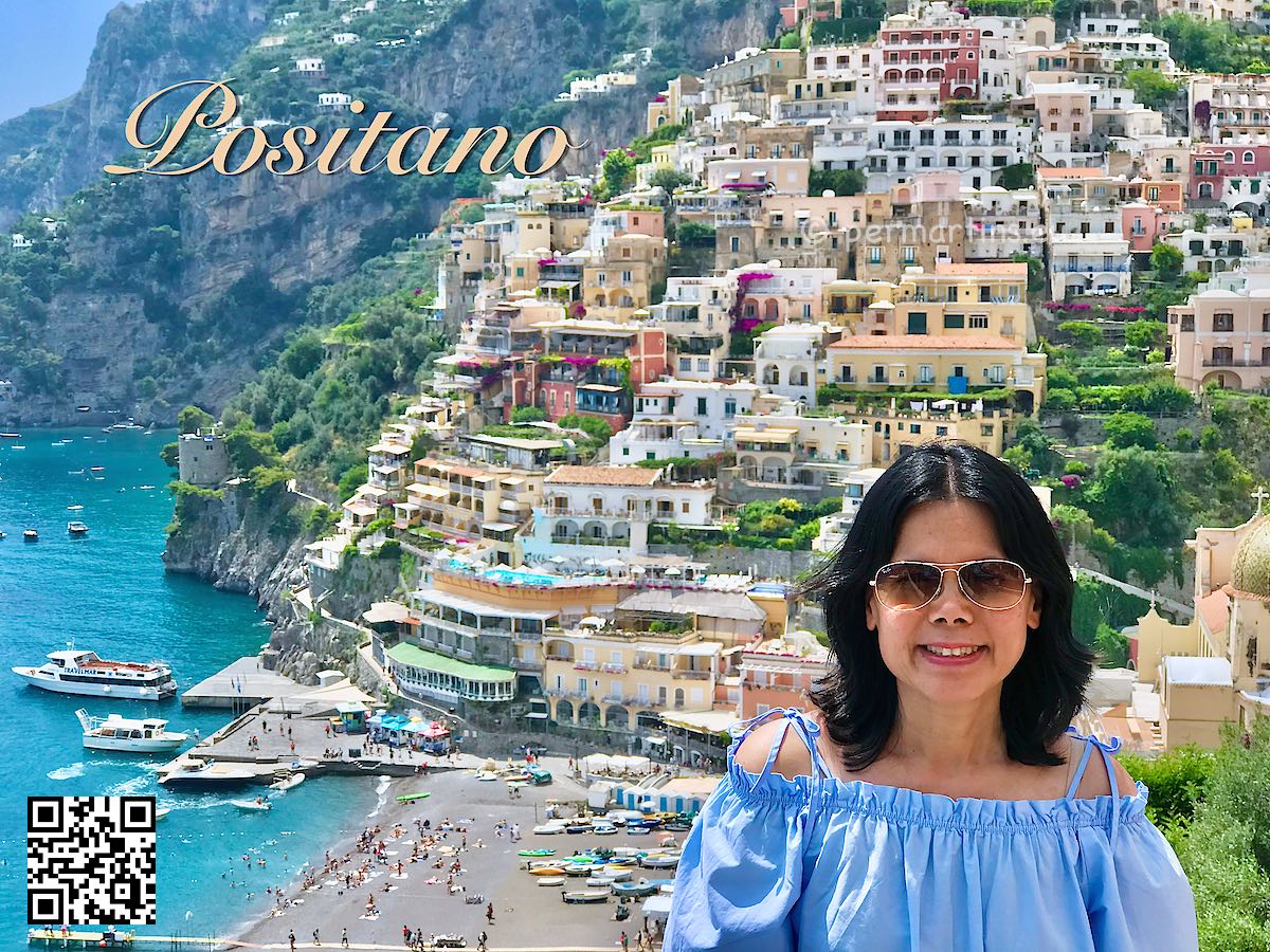 Italy Positano women in blue and sunglasses with a view over Positano houses beach and port.